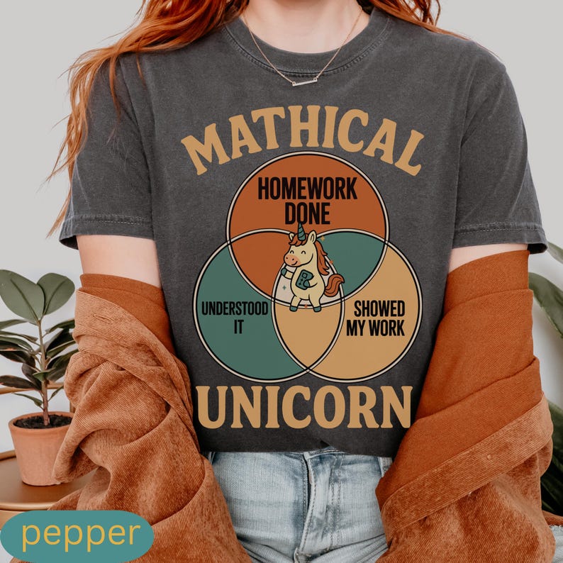 Peut inclure: T-shirt gris fonc&eacute; avec un motif repr&eacute;sentant une licorne dans un diagramme de Venn. Le diagramme comprend les mots "Mathical", "Homework Done", "Understood It" et "Showed My Work". Le mot "Unicorn" est en bas.