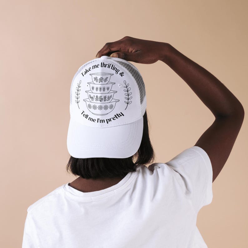Puede incluir: Gorra de camionero blanca con parte trasera de malla y visera curva. La parte delantera presenta un gr&aacute;fico negro de cuencos apilados y el texto "Take me thrifting & Tell me I'm pretty."