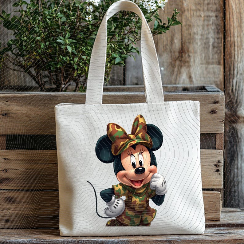 Pode incluir: Uma sacola de lona branca com um gr&aacute;fico da Minnie Mouse vestindo uma roupa e um la&ccedil;o com estampa de camuflagem. A bolsa tem linhas onduladas finas em cinza claro impressas no tecido, criando um padr&atilde;o sutil no fundo branco.