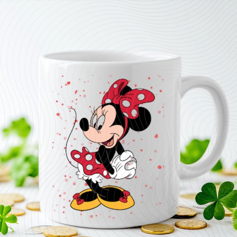 May include: White ceramic mug featuring a colorful illustration of Minnie Mouse. Minnie is depicted in her classic outfit: a red dress with white polka dots, a matching bow, and yellow shoes. The mug has a curved handle.