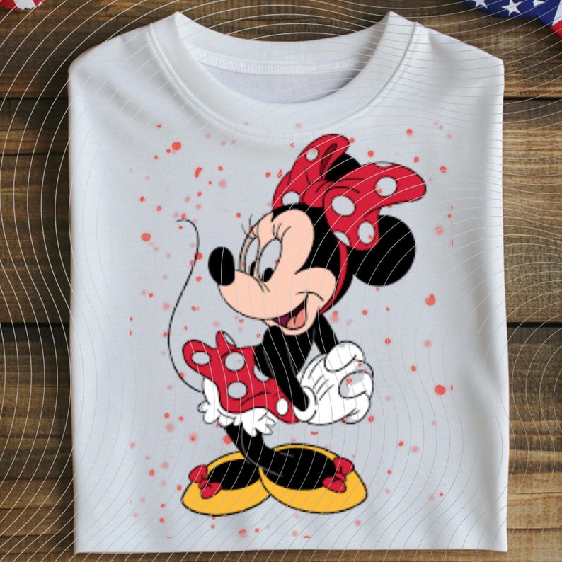 May include: White crew neck sweatshirt featuring a colorful Minnie Mouse graphic. Minnie Mouse is depicted in her classic outfit, with a red polka dot bow, dress, and shoes. The sweatshirt has a relaxed fit and is decorated with red speckles.