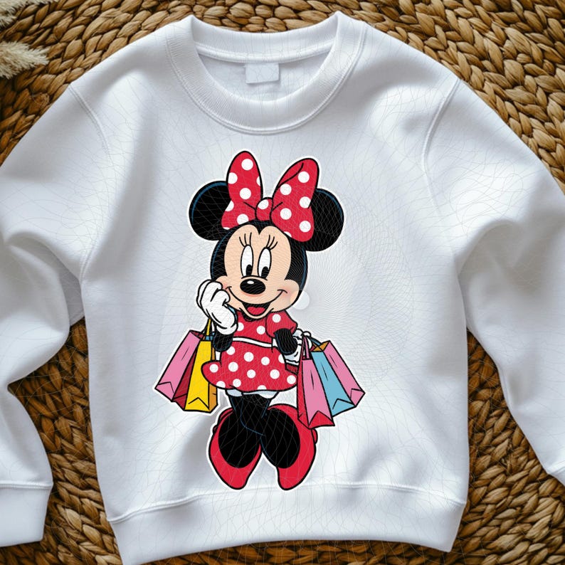 May include: White sweatshirt featuring a cartoon illustration of Minnie Mouse. Minnie is depicted in a red polka-dot dress and bow, holding shopping bags. The design is centered on the front of the sweatshirt.