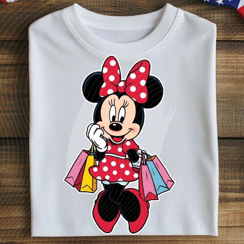 May include: White crew neck sweatshirt featuring a Minnie Mouse graphic. Minnie is depicted in a red polka dot dress and bow, holding shopping bags. The design is colorful and playful, perfect for Disney fans.