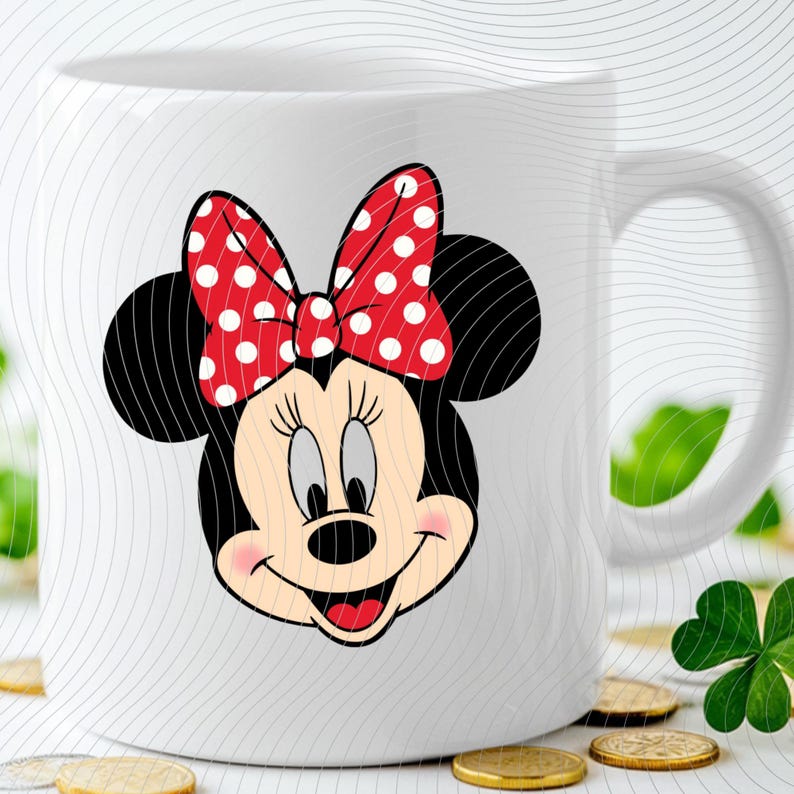 Op de afbeelding: Witte keramische mok met een Minnie Mouse-afbeelding. De afbeelding toont Minnie's gezicht met een rode strik met witte stippen. De mok heeft een gebogen handvat en een glanzende afwerking.