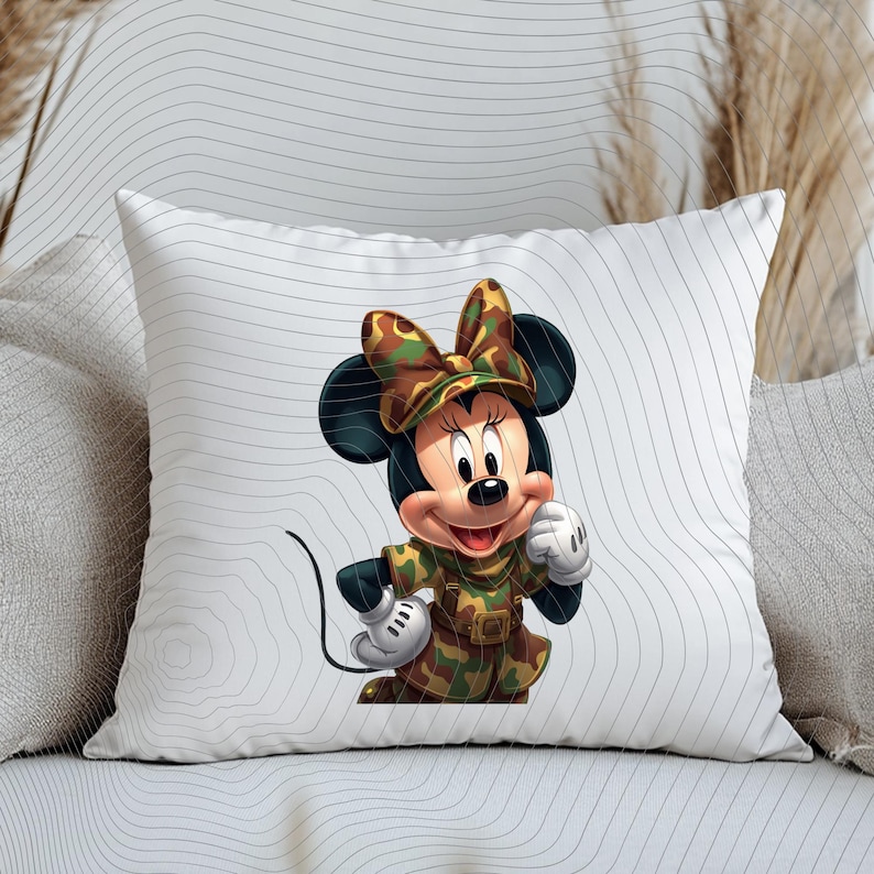 Pode incluir: Uma almofada quadrada branca com um gr&aacute;fico central de um rato de desenho animado vestindo uma roupa com estampa de camuflagem e um la&ccedil;o combinando. O personagem tem orelhas pretas, luvas brancas e um sorriso em um fundo branco.