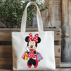 May include: A white canvas tote bag featuring a cartoon illustration of Minnie Mouse in a red polka-dot dress and bow, holding shopping bags. The bag has a rectangular shape with a handle.