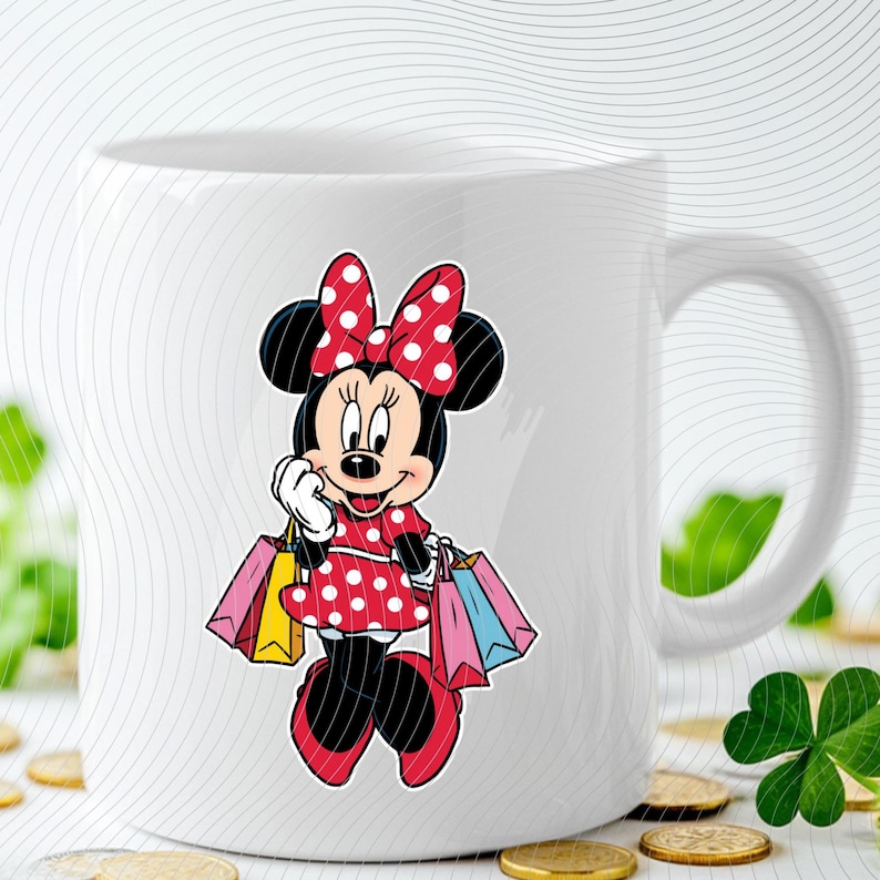 May include: White ceramic mug featuring a colorful Minnie Mouse design. Minnie is depicted in a red polka-dot dress and bow, holding shopping bags. The mug has a curved handle and a glossy finish, perfect for hot beverages.