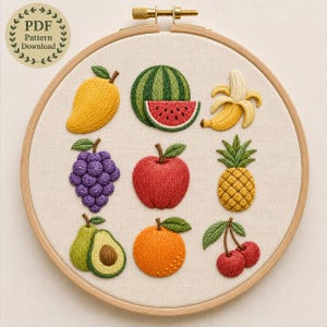 May include: An embroidery hoop containing a fabric panel with nine stitched fruit designs: a yellow mango, a watermelon slice, a peeled banana, purple grapes, a red apple, a yellow pineapple, an avocado, an orange, and two red cherries.