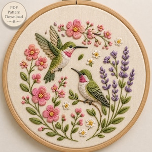 Puede incluir: Un bastidor de bordado circular de madera que contiene un panel de tela con un diseño bordado a mano de dos colibríes, flores rosas, flores blancas y ramas de lavanda moradas. El texto PDF Pattern Download es visible en la esquina superior izquierda.