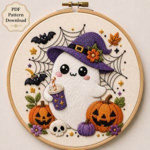 Peut inclure: Un tambour à broder présentant un fantôme blanc portant un chapeau de sorcière violet avec une fleur orange, tenant une tasse violette avec une paille. Le motif inclut deux citrouilles d'Halloween orange, un petit crâne, des chauves-souris et des toiles d'araignée.