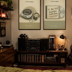 May include: A set of two rectangular wall prints with black frames, titled Set of 2 Prints. The prints feature the text Nostalgic Sound of Decades and the 90's, with illustrations of a portable CD player with headphones and a CD case labeled The Nostalgia Collection.