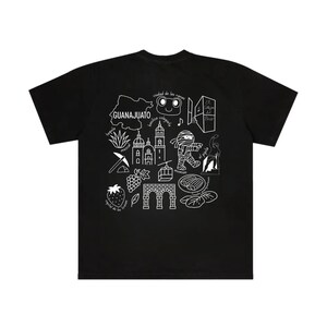 Puede incluir: Camiseta negra con un dise&ntilde;o gr&aacute;fico blanco que presenta la palabra "GUANAJUATO" y varias ilustraciones. El dise&ntilde;o incluye un mapa, edificios y otros s&iacute;mbolos culturales. La camiseta est&aacute; hecha de un material suave.