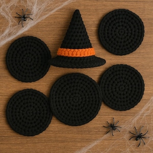 May include: A set of five circular black crocheted coasters arranged around a central black crocheted witch hat with an orange band. The items are displayed on a wooden surface with decorative white spider webs and three small black plastic spiders.