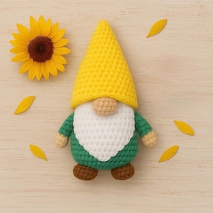 May include: A handmade crochet gnome with a yellow hat, green body, white beard, and brown shoes. A yellow sunflower and petals are arranged on a light wood surface. The gnome is a whimsical decorative item.