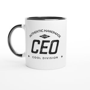Könnte beinhalten: Weißer Keramikbecher mit schwarzem Henkel und Rand. Der Becher trägt den Text "AUTHENTIC HANDMADE 2026 CEO COOL DIVISION" in schwarzer, verblichener Schrift. Auf beiden Seiten der Wörter befindet sich eine Stern-Grafik.