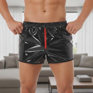 Puede incluir: Shorts negros brillantes con cremallera roja. Los shorts tienen un acabado brillante y un diseño clásico. Los shorts tienen un ribete negro en los bordes y bolsillos laterales.