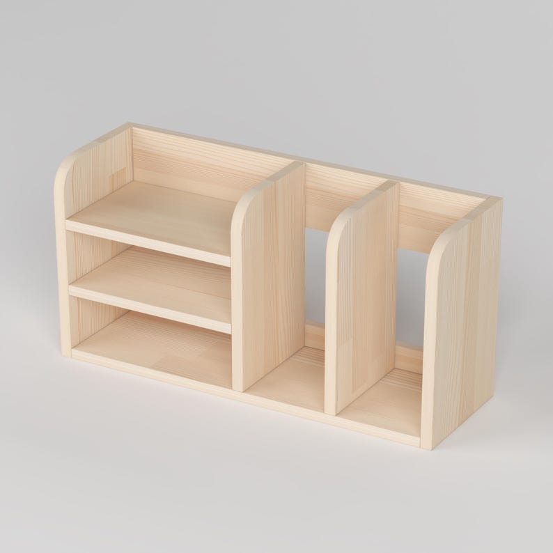 May include: A light-colored wooden desk organizer with three compartments. The organizer has two shelves on the left side and a larger open space on the right. The wood has a natural finish.