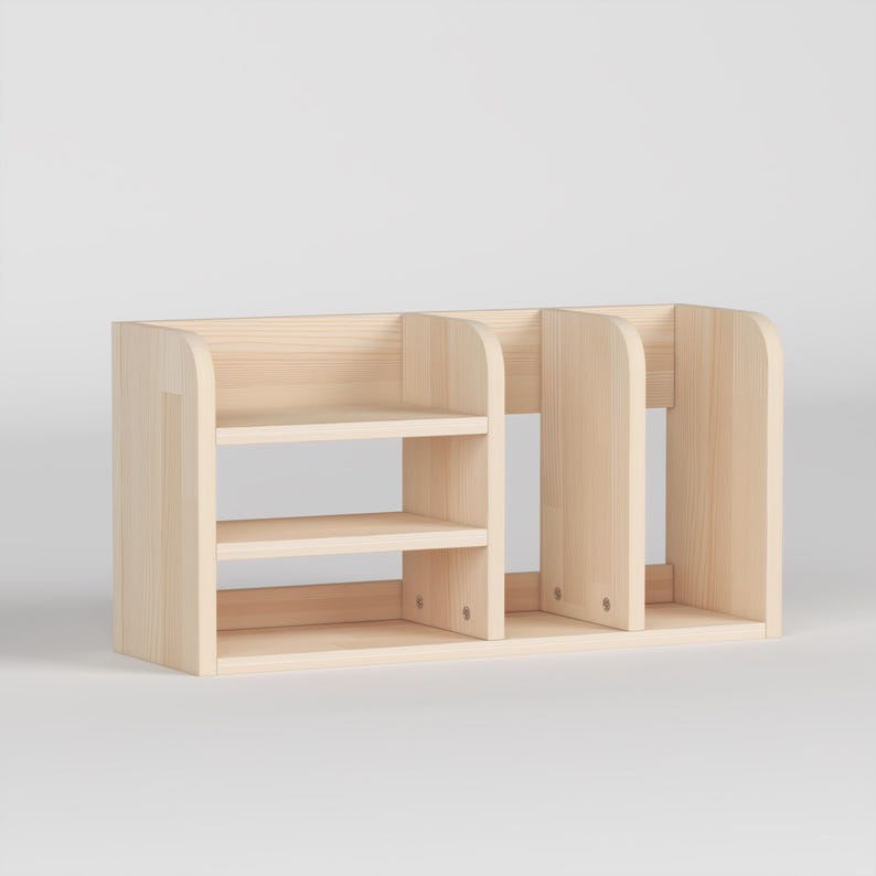 May include: A light-colored wooden desk organizer with multiple compartments. The organizer has two shelves on the left side and three vertical dividers on the right. The wood has a natural finish.