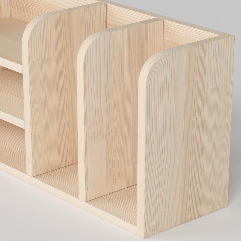 May include: A light-colored wooden organizer with multiple compartments. The organizer has a rectangular base and vertical dividers with rounded tops. The wood grain is visible, and the overall design is simple and functional.