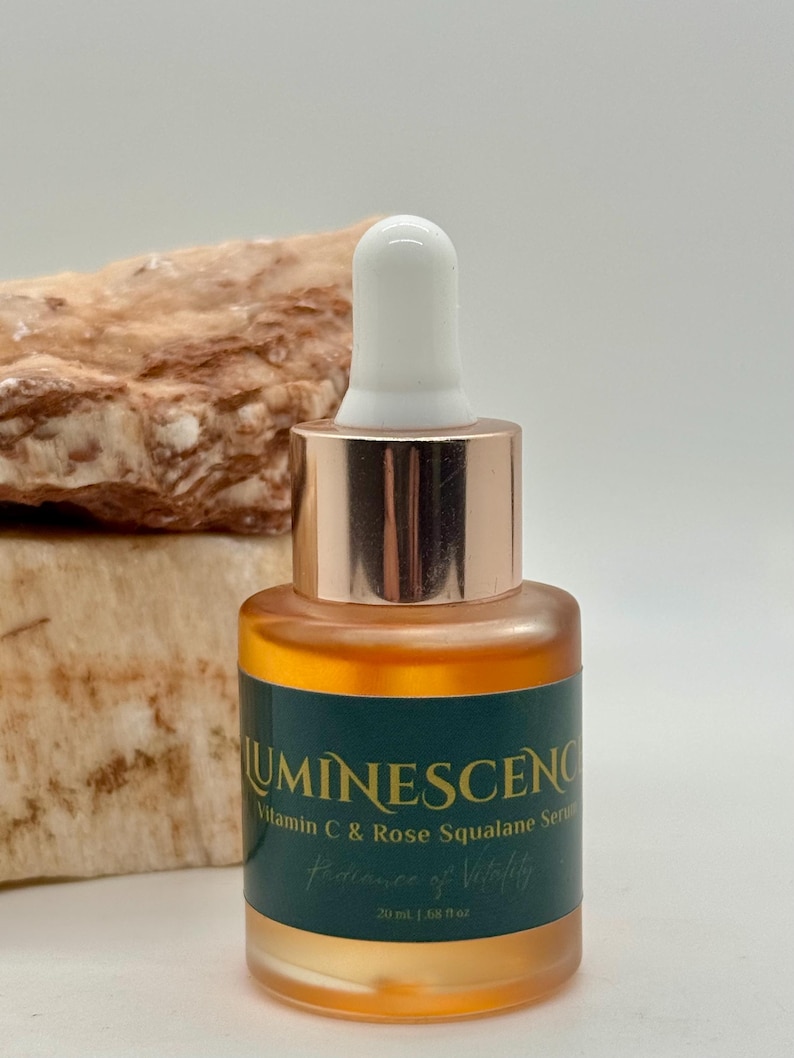 K&ouml;nnte beinhalten: Eine Glasflasche Serum mit wei&szlig;em Tropferaufsatz und kupferfarbenem Kragen. Die Flasche hat ein dunkelgr&uuml;nes Etikett mit dem Wort "LUMINESCENCE" und dem Text "Vitamin C & Rose Squalane Serum". Die Flasche enth&auml;lt 20 ml Serum.