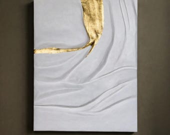 May include: Abstract wall art featuring a textured white surface with a gold leaf accent. The gold leaf flows across the canvas, creating a striking contrast. The artwork has a modern, minimalist aesthetic.