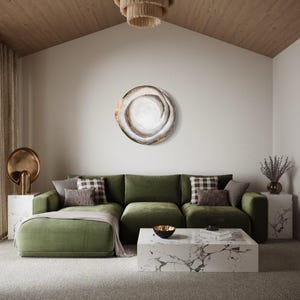 May include: A modern living room with a green sectional sofa, marble coffee table, and a decorative wall art piece. The room features a neutral color palette with a textured rug and a wooden ceiling. A tiered chandelier hangs from the ceiling.