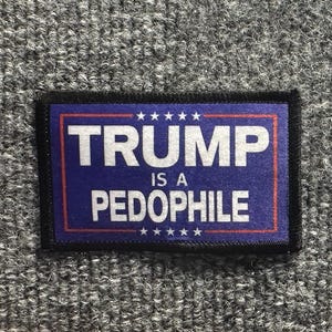 May include: A rectangular fabric patch with a dark blue background and a thin red border. The text TRUMP IS A PEDOPHILE is printed in large white capital letters. Five small white stars are positioned in a horizontal row above and below the text.