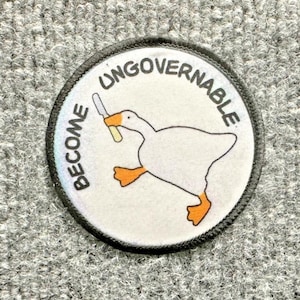May include: A circular embroidered patch with a white background and a dark border. The design features a white goose with orange feet and beak, holding a silver knife in its beak. The text BECOME UNGOVERNABLE is printed in black letters.