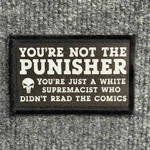 May include: A rectangular black patch with white embroidered text that reads: YOU'RE NOT THE PUNISHER, YOU'RE JUST A WHITE SUPREMACIST WHO DIDN'T READ THE COMICS. The patch features a small white skull icon on the left side of the text.