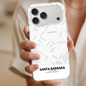 以下が含まれることがあります： サンタバーバラ（カリフォルニア）の地図が描かれた白い携帯電話ケース。通りの名前と都市名が下部に表示されています。ケースには、座標34.4208° N、119.6982° Wも含まれています。