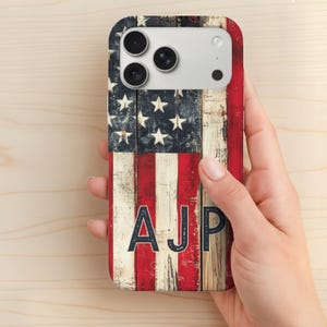May include: A phone case featuring a distressed American flag design with red and white stripes and a blue field of stars. The initials "AJP" are displayed in bold, dark letters. The case has a wooden plank appearance.