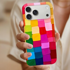 Könnte beinhalten: Eine Smartphone-Hülle mit einem lebendigen, mehrfarbigen Mosaikmuster aus dicken, strukturierten Pinselstrichen in Rot, Gelb, Pink, Grün, Blau und Violett. Die Hülle verfügt über einen rechteckigen Ausschnitt für die Kamera mit drei Linsen.