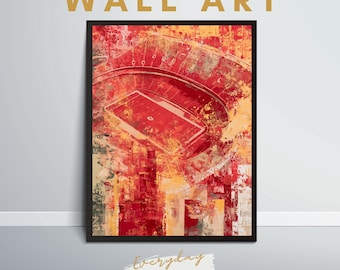 May include: A framed wall art print featuring an abstract, painterly depiction of a football stadium in shades of red, orange, and yellow. The artwork displays a high-angle view of the field and seating bowl with textured, splattered paint effects.