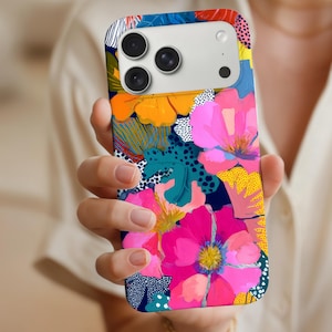 May include: A phone case with a bright floral pattern. The case displays large pink, orange, and blue flowers on a dark blue backdrop. The design incorporates white polka dots and yellow accents.
