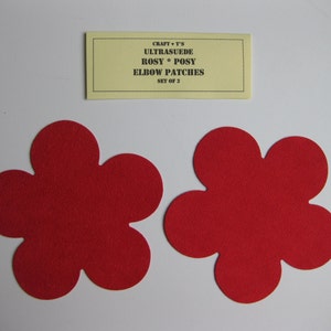 Puede incluir: Dos parches para codos de fieltro rojo en forma de flor. Los parches están hechos de ultrasuede y se venden en un juego de dos. El texto en la etiqueta dice "Craft T's Ultrasuede Rosy Posy Elbow Patches Set of 2".