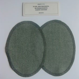 以下が含まれることがあります： 白い背景に、緑色のヘリンボーン柄の肘当てが2つ。パッチは楕円形で、ステッチが施された縁取りがされています。カードには「CRAFT ♥ T'S PLAID, HOUNDSTOOTH, OR HERRINGBONE ELBOW PATCHES SET OF 2」と書いてあります。