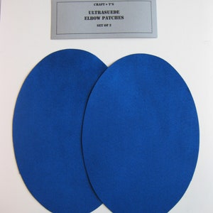 Może przedstawiać: Dwie owalne łaty na łokcie z Ultrasuede w kolorze królewskim niebieskim. Łaty są na białym tle. Etykieta nad łatami głosi "CRAFT T'S ULTRASUEDE ELBOW PATCHES SET OF 2".