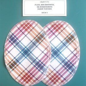May include: Set of two plaid elbow patches. The patches are oval shaped and have a white background with red, blue, and brown plaid pattern. The patches are sewn around the edges.