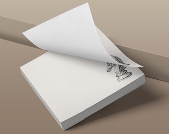 May include: A square stack of white paper sheets with a top sheet partially peeled back to reveal a black and white line drawing of a chess knight piece printed on the corner of the paper underneath. The paper stack has a clean, smooth texture.