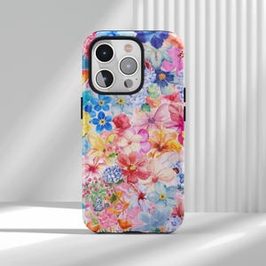 May include: A floral phone case featuring a vibrant watercolor design. The case is covered in a variety of colorful flowers in shades of pink, blue, yellow, and orange. The case has a glossy finish and a black border.