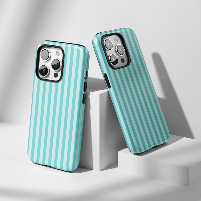 May include: Two teal and white striped phone cases. The cases have a black border around the camera and a black side button. The cases are leaning against a white background.