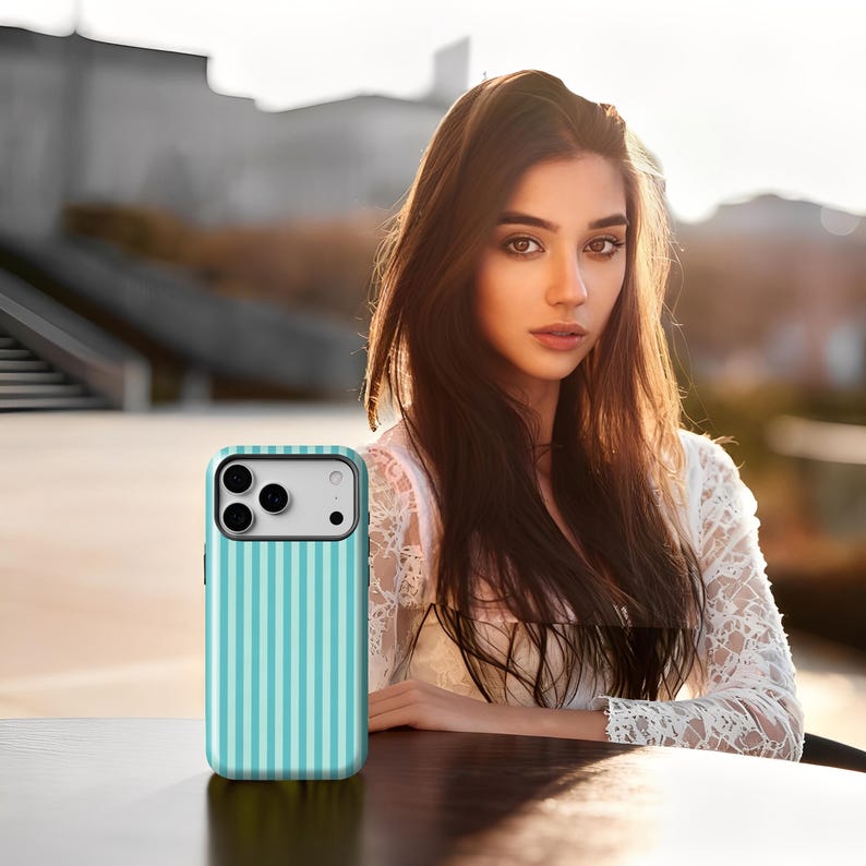 May include: A teal and white striped phone case. The case has a vertical stripe pattern and a camera cutout. The phone case is on a dark surface.