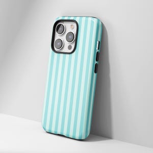 May include: A smartphone case with a vertical striped pattern in light blue and white. The case has a black border around the camera and a glossy finish. The phone case is leaning against a white surface.