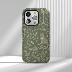 May include: Green phone case with a woodland design featuring a fox, rabbit, tree, and various plants. The case has a matte finish and a black border, providing protection and style.