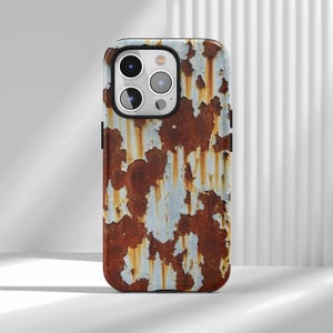 May include: A phone case featuring a weathered, rusty metal design. The case has a brown and orange color scheme with patches of white and blue, creating a distressed look. The case has a camera cutout and black side buttons.