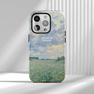 May include: A smartphone case featuring an impressionistic oil painting of a lush green meadow filled with wildflowers under a cloudy blue and yellow sky. The text "oh, how He loves us" is printed in white in the centre of the phone case design.