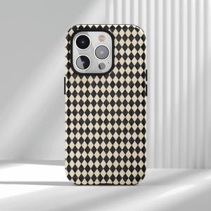 Op de afbeelding: Een telefoonhoesje met een zwart en crèmekleurig ruitpatroon. De hoes heeft een uitsparing voor de camera en zwarte zijaccenten. Het ontwerp is een herhalend patroon van zwarte ruiten op een crèmekleurige achtergrond.