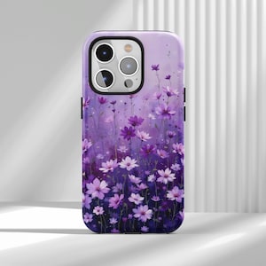 Könnte beinhalten: Handyhülle mit einem Aquarell-Blumenmuster in Lila- und Weißtönen. Die Hülle hat eine glänzende Oberfläche und einen Schutzstoßfänger. Die Blumen sind in einem Feld dargestellt, mit einem weichen, verschwommenen Hintergrund.
