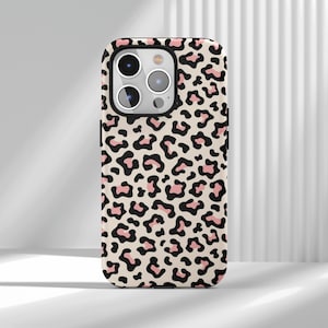 May include: A phone case with a leopard print pattern. The case has a beige base with black and pink spots. It has a black border and cutouts for the phone's camera and buttons.