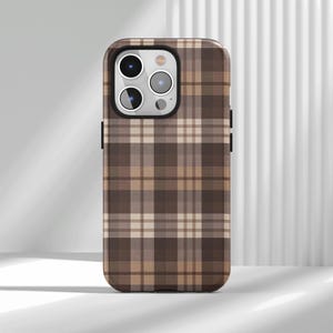 Könnte beinhalten: Eine Smartphone-Hülle mit einem Karomuster in Braun, Beige und Creme. Die Hülle hat eine rechteckige Form mit abgerundeten Ecken und einer Aussparung oben links für ein Dreifach-Kamerasystem, das die gesamte Rückseite der Hülle bedeckt.